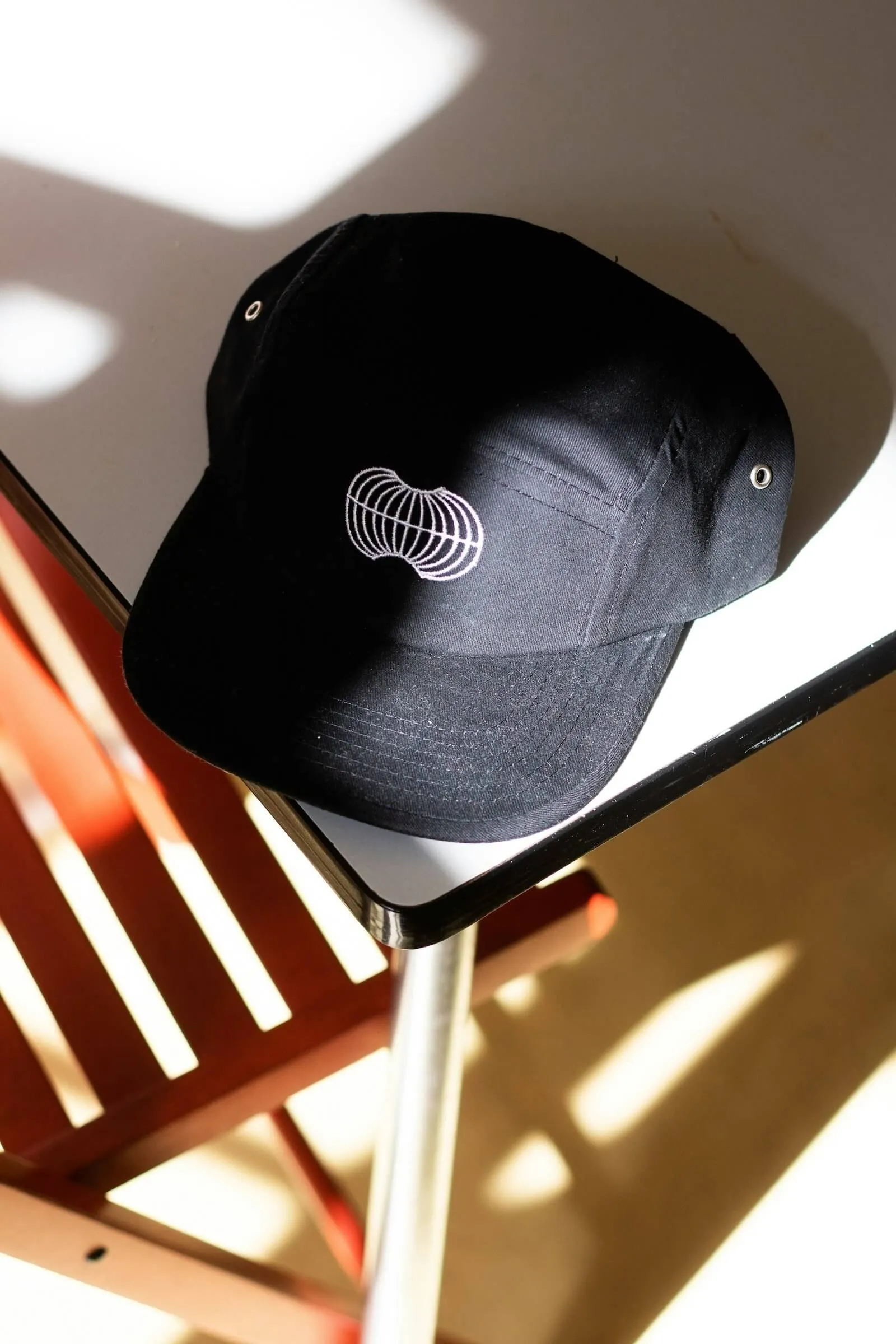 Casquette noire brodée, posée sur un présentoir de l’atelier